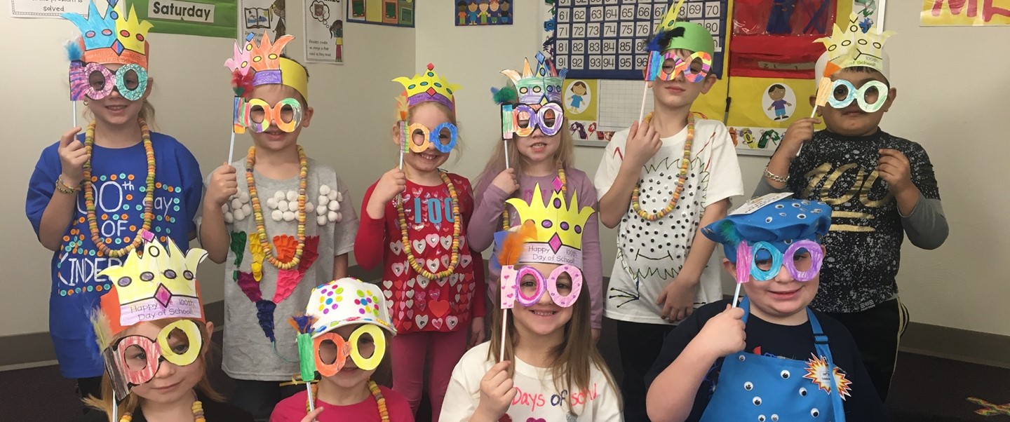 Kindergarten students holding 100 day masks to their face