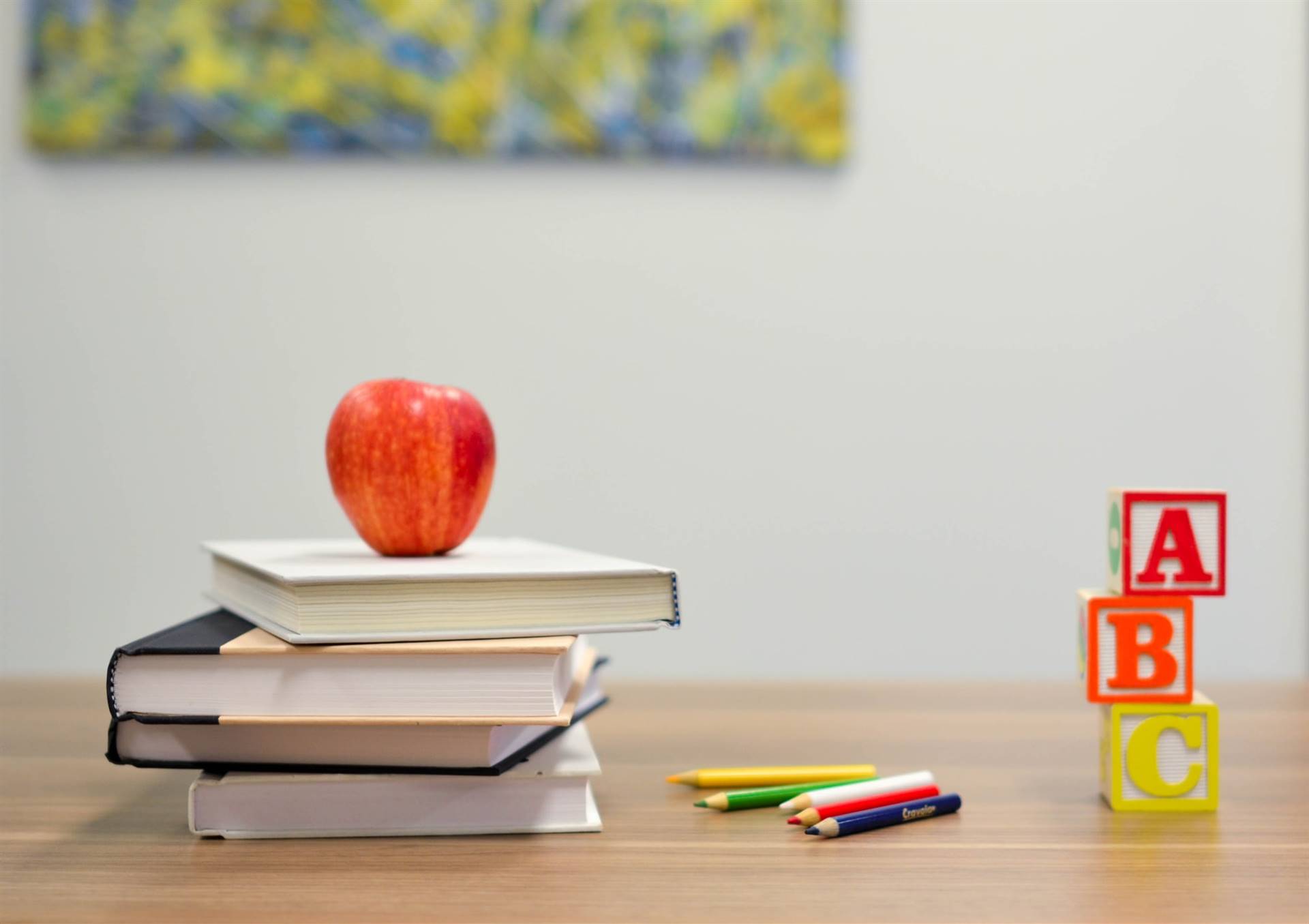 Apple on books with colored pencils and ABC blocks